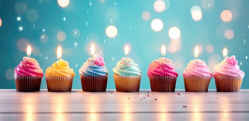 A row of beautiful cakes with cream tops and burning candles on a beautiful bright background - obrazy, fototapety, plakaty
