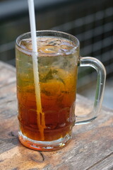 Es Teh. iced tea is a fresh drink made from tea, water, sugar, and ice cubes. iced tea in a clear glass on a brown wooden table. Indonesian drink. 