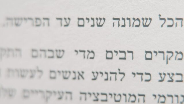 A macro smooth and detailed pan left shot of a book in Hebrew, black letters on white paper, 4K video