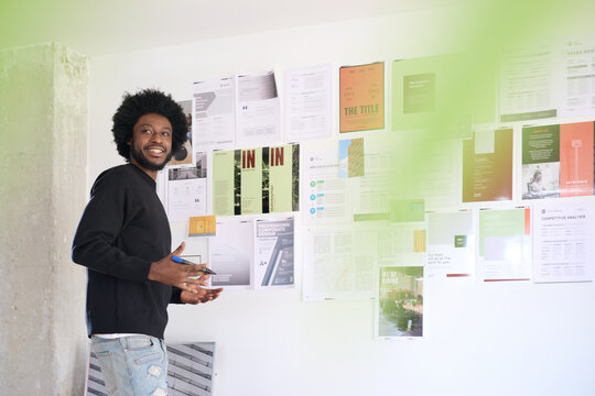 Creative Professional Presenting Design Work. Designer showcasing project layouts on wall