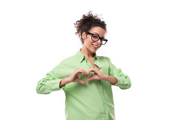 pretty young brunette curly woman in glasses is dressed in a green shirt on a white background with...