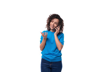 a slender young curly woman dressed in a blue summer jacket speaks on the phone