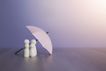 Umbrella and wooden dolls with copy space. Family protection and insurance coverage concept.