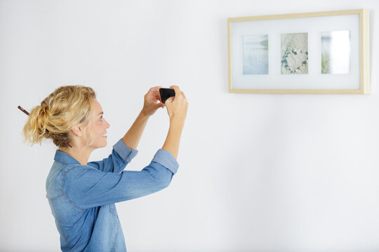 fashionable woman taking picture of a display of paintings