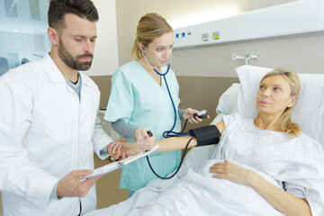 doctor and nurse taking blood pressure of senior woman