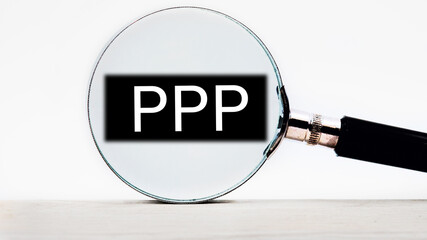 Paycheck Protection Program PPP lettering on through a magnifying glass on a light background
