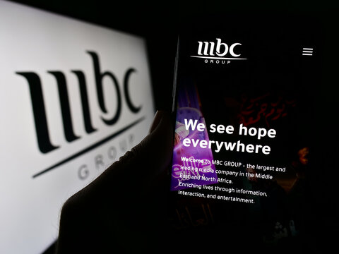 Stuttgart, Germany - 11-29-2023: Person holding cellphone with webpage of Saudi Arabian media company MBC Group in front of business logo. Focus on center of phone display.