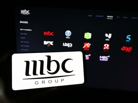 Stuttgart, Germany - 11-29-2023: Person holding smartphone with logo of Saudi Arabian media company MBC Group in front of website. Focus on phone display.