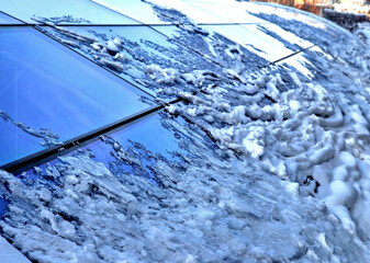 roof windows clogged with snow. roofing of greenhouse or atrium. snow is melting and coming down,...