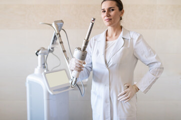 female doctor holds in her hands a carbon dioxide laser with a phallic attachment for vaginal rejuvenation. Hardware cosmetology and medicine. Skin tightening, scar removal, stretch marks and lifting  - obrazy, fototapety, plakaty