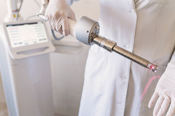 female doctor holds in hands carbon dioxide laser with phallic attachment for vaginal rejuvenation. Hardware cosmetology and medicine. Skin tightening, scar removal, stretch marks and lifting closeup - obrazy, fototapety, plakaty