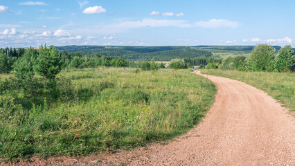 The road through a field overgrown with grass in the countryside. Nature in the village. Summer landscape in the village.
