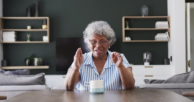 Happy senior african american woman having video call at home talking and waving, slow motion