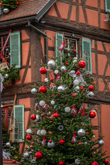 Christmas tree with red and silver ornaments in the front of a traditional timber framed house in...
