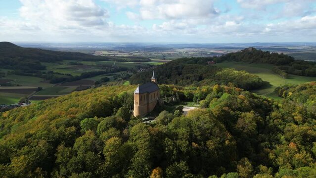 Drone orbiting a chapel in the middle of a forest during daytime