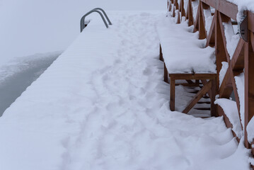 WINTER ATTACK - A frozen lake and a wooden recreation pier covered with snow
