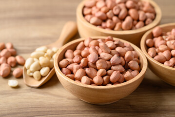 Peanut in bowl with spoon on wooden background