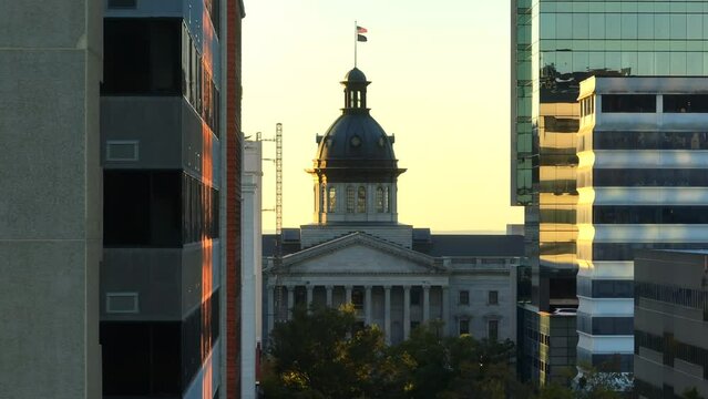 Skyscrapers in downtown Columbia, SC revealing South Carolina State House during sunrise. Aerial long zoom lens parallax shot.
