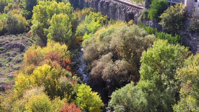 Vibrant autumn foliage adorns the banks of the Hrazdan River on a sunny day in the scenic Hrazdan Gorge, captured from above, uhd, 4k, 3840, 2160