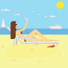 Obraz na płótnie Canvas A girl on the beach sunbathing and blogging on the phone