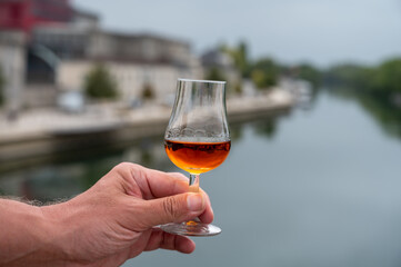 Tasting of cognac alcohol drink and view on old streets and houses in town Cognac, Grand Champagne, Charente, strong spirits distillation industry, France