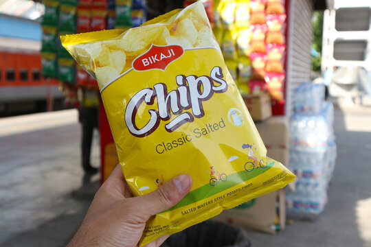 A young Caucasian man holds a pack of Bikaji brand classic salty chips in his hand in Haridwar, India, April 20, 2023