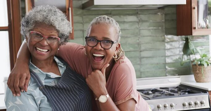 Portrait of happy senior african american female friends cooking in kitchen, copy space, slow motion