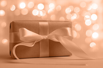 Gift box on a beige background with bokeh. Valentine's day. Holiday of lovers. Demonstrating color of 2024 year - peach.