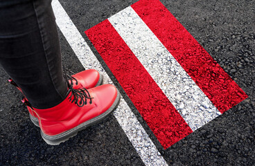 a womman with a boots standing on asphalt next to flag of Austria and border
 - obrazy, fototapety, plakaty