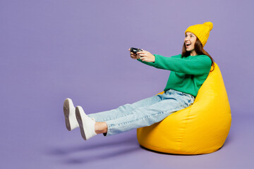Full body young woman wear green sweater yellow hat casual clothes sit in bag chair hold in hand...