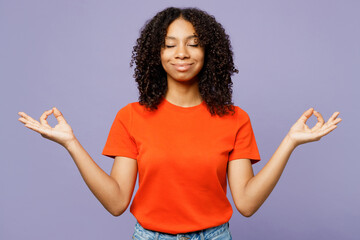 Little kid teen girl of African American ethnicity wear orange t-shirt hold hands in yoga om aum gesture relax meditate try calm down isolated on plain purple background. Childhood lifestyle concept. - Powered by Adobe