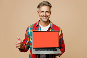Adult fun IT man wear red shirt white t-shirt casual clothes hold use work on laptop pc computer with blank screen workspace area show thumb up isolated on plain pastel light beige color background.