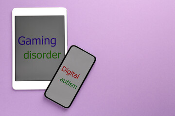 Addictive behavior. Tablet, smartphone with phrases Gaming Disorder and Digital Autism on violet background, flat lay. Space for text