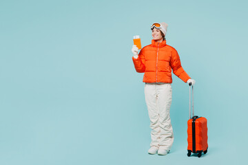 Traveler fun skier woman wears padded windbreaker jacket ski goggles mask hold passport ticket bag...