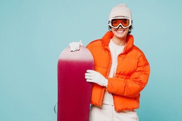 Young happy woman wear warm padded windbreaker jacket hat ski goggles mask hold snowboard look...