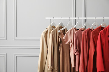 Rack with different stylish women`s clothes near grey wall, space for text