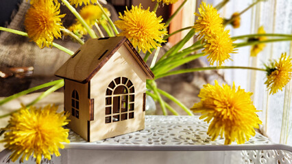 miniature toy house in grass, dandelion flowers, spring natural background. symbol of family....