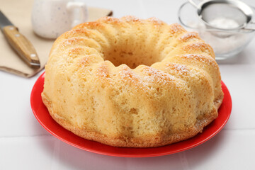 Delicious freshly baked sponge cake on white tiled table, closeup