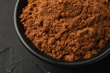 Aromatic cinnamon powder on black table, closeup