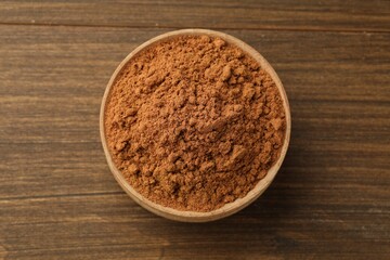 Aromatic cinnamon powder on wooden table, top view