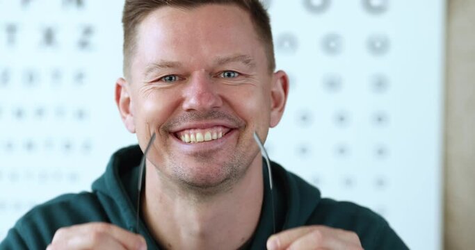 Portrait of young smiling man takes off glasses. laser vision correction concept