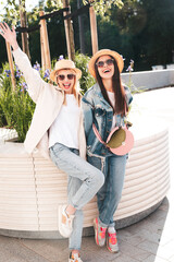 Two young beautiful smiling hipster female in trendy summer clothes. Carefree women posing in the...