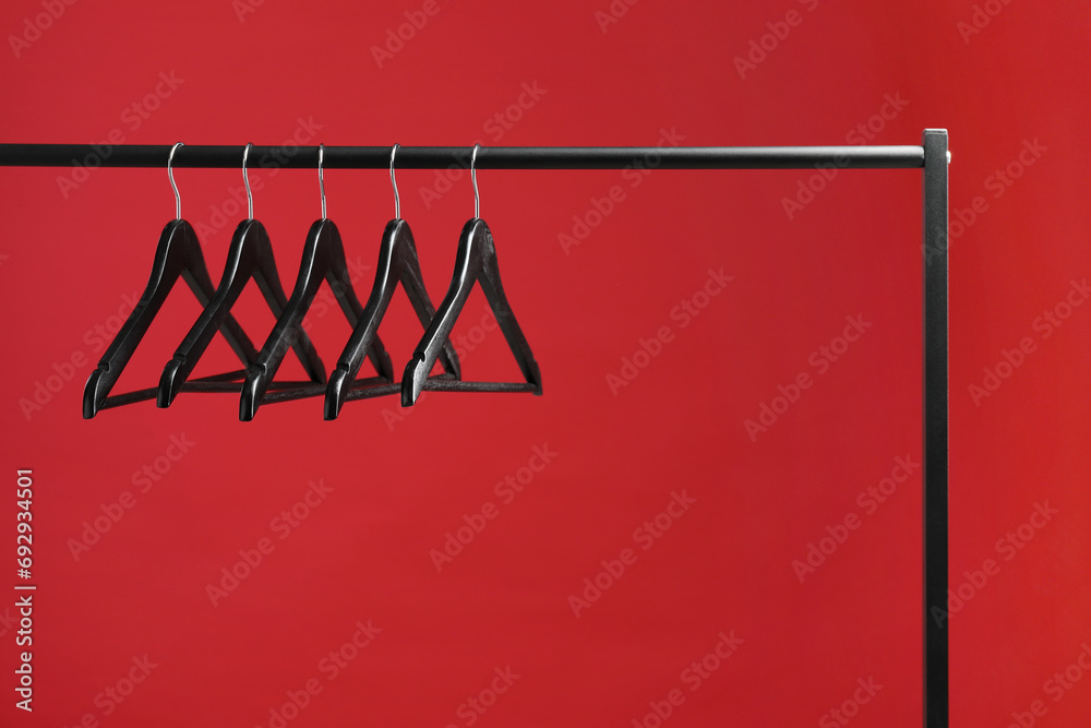 Wall mural black clothes hangers on rack against red background. space for text