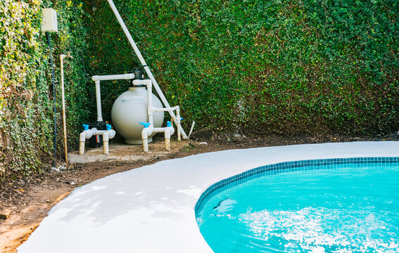 Pool pump with sand filter installed near of swimming pool. Home swimming pool filter and treatment plant installed. Pool purification and maintenance system