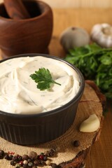 Tasty sauce with garlic, spices and parsley on table, closeup