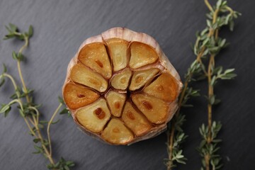 Head of fried garlic and thyme on dark gray table, closeup
