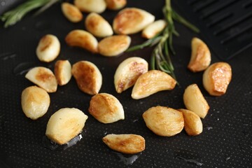 Frying pan with fried garlic cloves, closeup