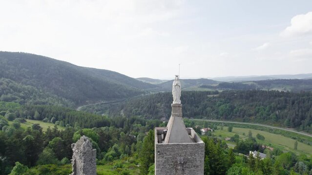 Virgin Mary Statue On Tower Of Chateau de Luc, Castle Ruins In Luc, France. aerial pullback reveal