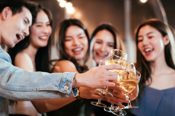 Group of Asian friends smiling and toasting glass of wine together to celebration at the party. Congratulations on success achievement. People hangout on weekend night.