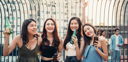 Group of Asian girls holding bottle of beer smiling and dancing at the party restaurant. Friends...